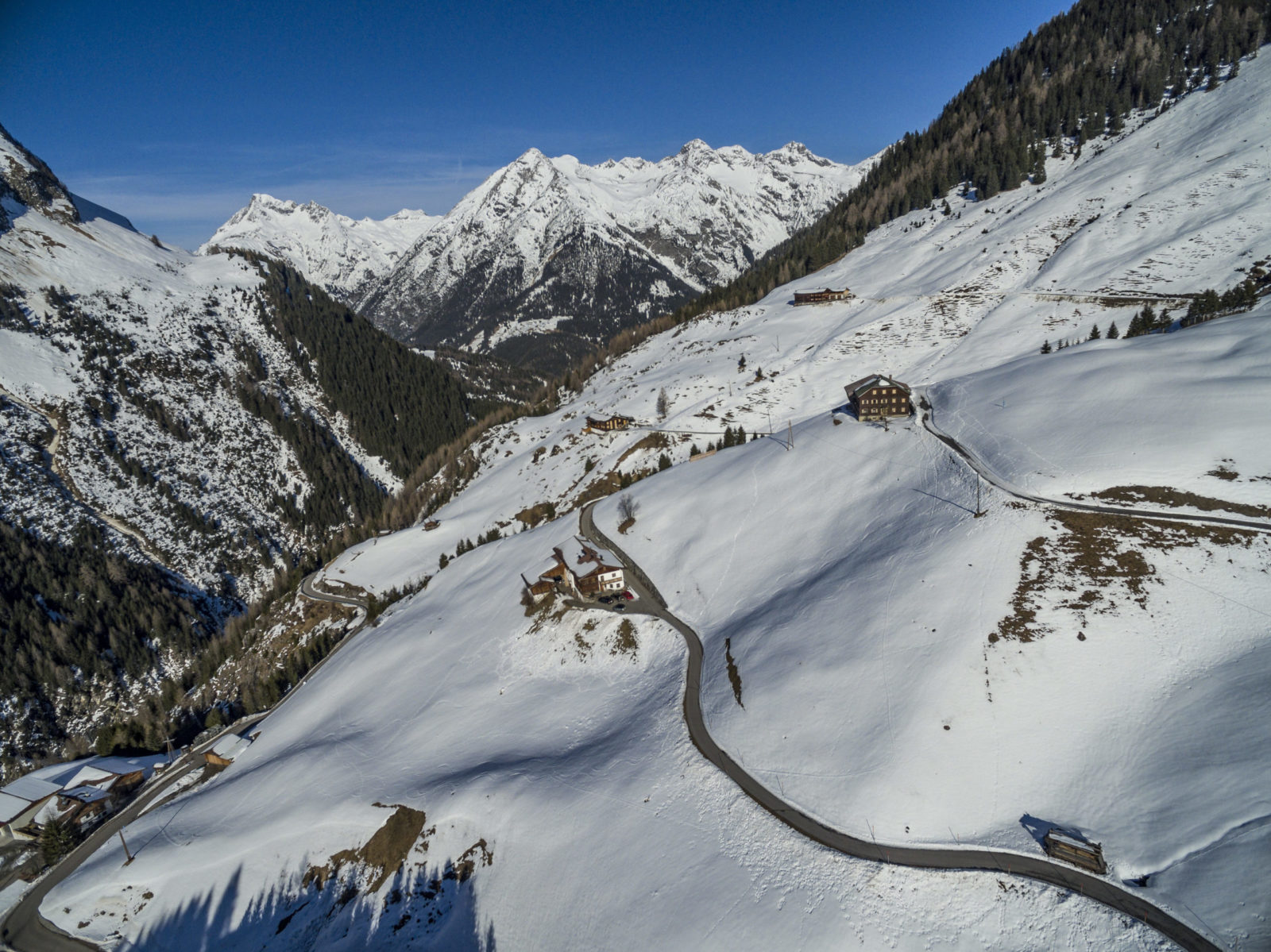 Drohnenaufnahme einer verschneiten Alpenstraße